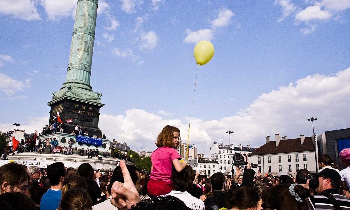Crowd gathered in a Paris square under a blue sky